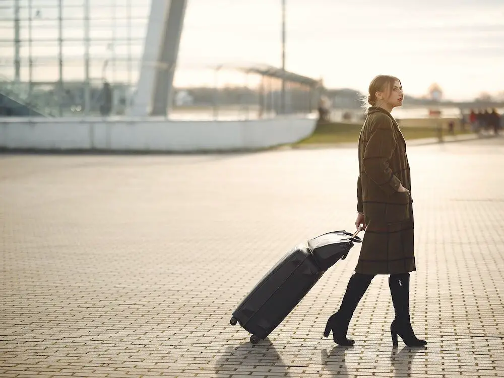 A young woman with a suitcase walking to the airport